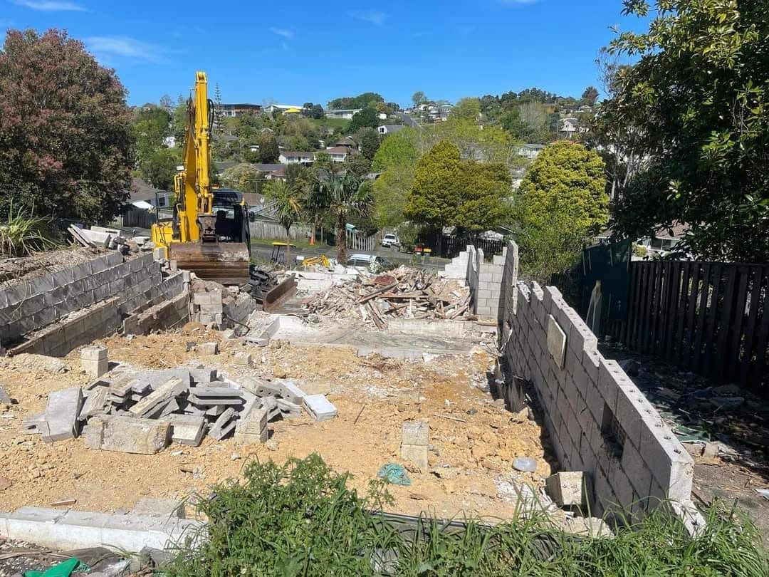 Excavator taking down a block wall during a partial demolition