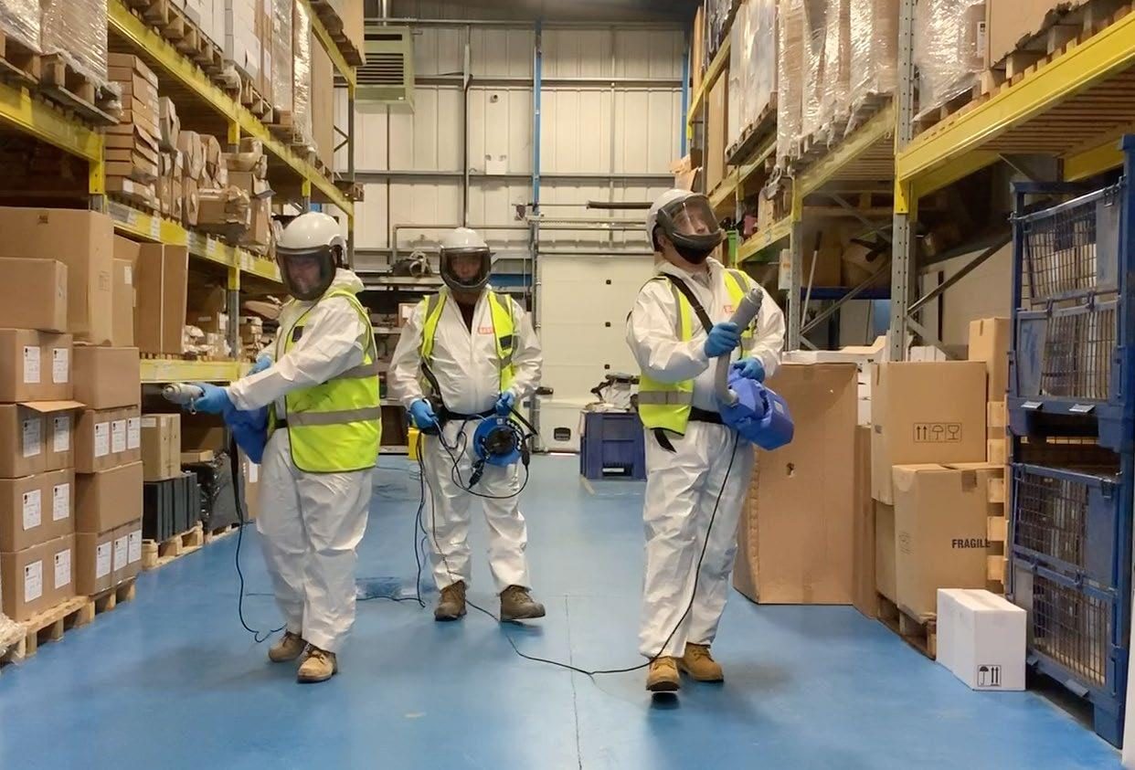 SES Group asbestos removal crew in PPE preparing a negative-pressure enclosure on a commercial site in Auckland